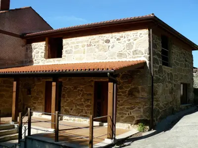 a stone house with a wooden porch in front of it at Apartamentos Rurales A Torre in Porqueira
