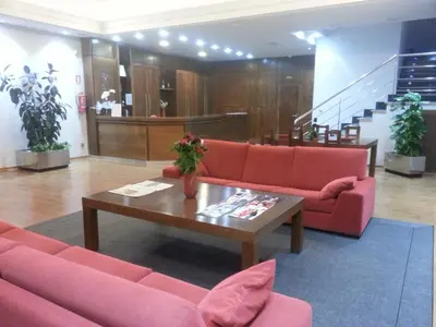 a lobby with red couches and a coffee table at Hotel San Cibrao in San Ciprián de Viñas