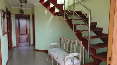 a spiral staircase in a living room with a chair at Casa Baixo O Castelo in Puente Caldelas