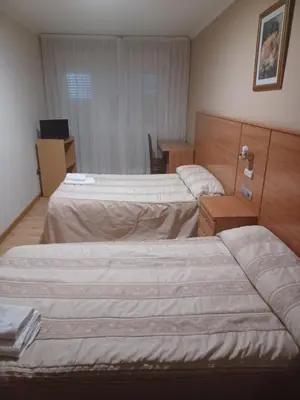 a hotel room with two beds and a desk at Hotel 2 de mayo 2 in Xinzo de Limia