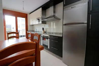 a kitchen with a stainless steel refrigerator and a table at APARTAMENTOS CASAS NOVAS in Silleda