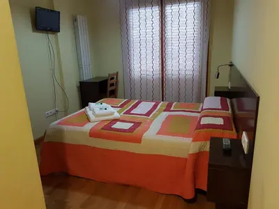 a bedroom with a bed with a colorful blanket and a window at APARTAMENTOS CASAS NOVAS in Silleda