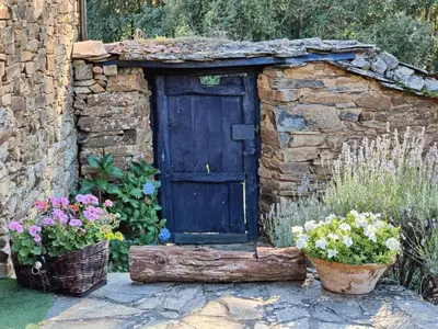 a stone building with a wooden door and some flowers at CASA COLOMBA in Santa Colomba de Somoza