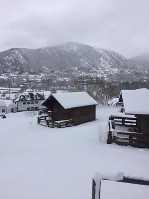 a group of huts covered in snow in front of a mountain at Camping Laciana Natura in Villablino
