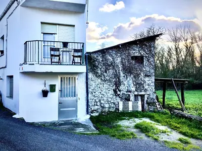 a white building with a balcony and a door at Casita junto al Río en un entorno natural in Monforte de Lemos