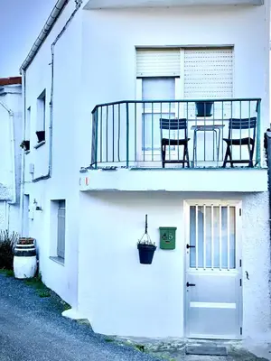 a white building with a balcony with two chairs and a door at Casita junto al Río en un entorno natural in Monforte de Lemos