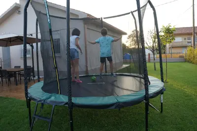 two children playing on a trampoline in a yard at Casa Asientos Boimorto in Boimorto