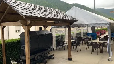 a grill under a wooden pavilion with tables and chairs at El cordal de laciana in Caboalles de Abajo