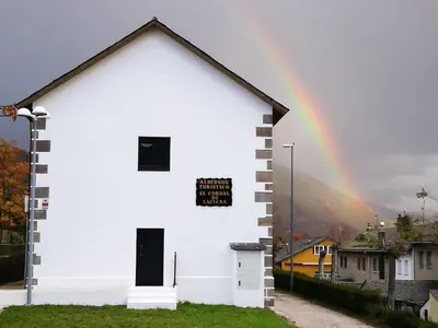 a rainbow over a white church with a rainbow at El cordal de laciana in Caboalles de Abajo