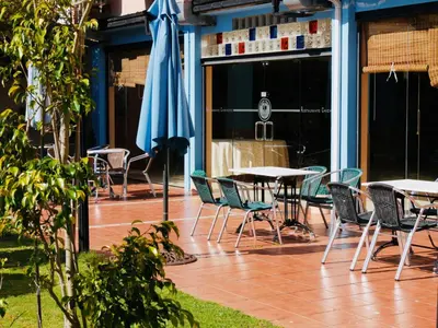 a patio with tables and chairs and a blue umbrella at Hotel Eumesa in Puentedeume
