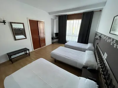 a hotel room with two beds and a window at Hotel Eumesa in Puentedeume