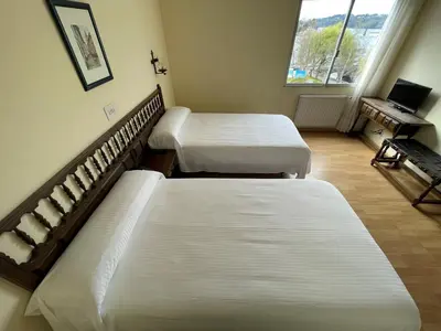 a room with two beds and a desk with a computer at Hotel Eumesa in Puentedeume