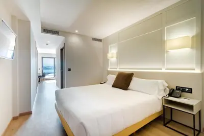 a bedroom with a white bed and a phone on a table at Playa de Foz Hotel & Spa by gaiarooms in Foz