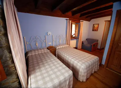 a bedroom with two beds and a chair at Casa Agudín in Cangas del Narcea