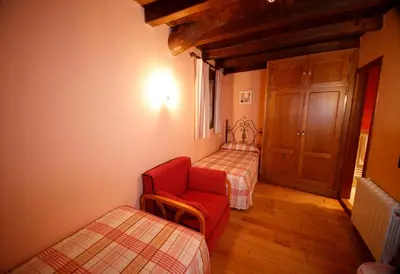 a room with two beds and a red chair at Casa Agudín in Cangas del Narcea