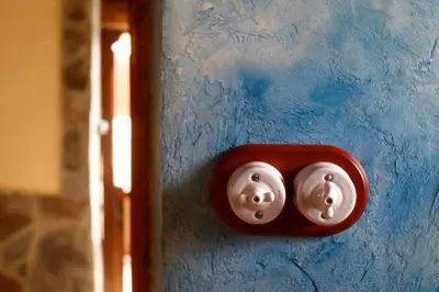 a red door knob with two faces on a blue wall at Casa Agudín in Cangas del Narcea
