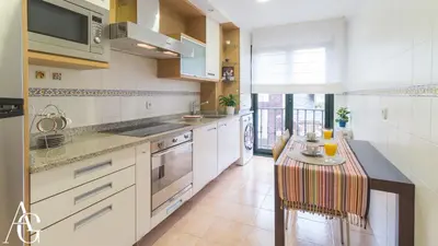 a kitchen with white cabinets and a table in it at Apartamento Plaza de España in Ribadeo