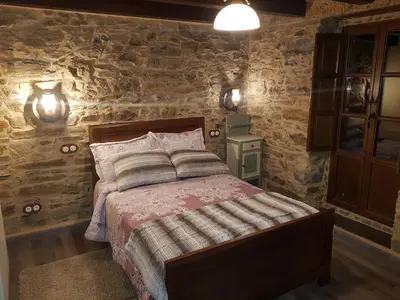 a bedroom with a bed and a stone wall at Apartamentos Rurales Casa Carmen in Pola de Allande