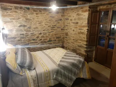 a bedroom with a bed in a brick wall at Apartamentos Rurales Casa Carmen in Pola de Allande