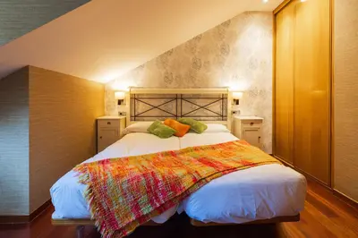 a bedroom with a bed with a colorful blanket on it at Apartamentos Casa Miño in Pola de Somiedo