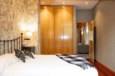 a bedroom with a bed and a wooden closet at Apartamentos Casa Miño in Pola de Somiedo