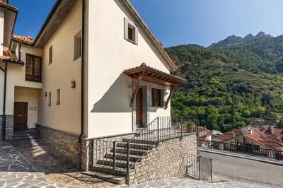 a building with stairs leading up to it with mountains in the background at Apartamentos Casa Miño in Pola de Somiedo
