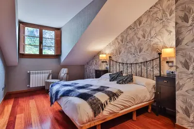 a bedroom with a large bed in a attic at Apartamentos Casa Miño in Pola de Somiedo