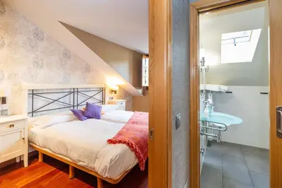 a bedroom with a bed and a bathroom with a sink at Apartamentos Casa Miño in Pola de Somiedo