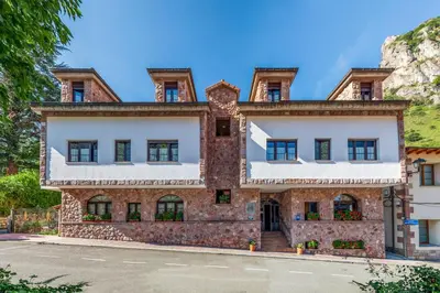 an old stone building with a mountain in the background at Hotel Casa Miño in Pola de Somiedo