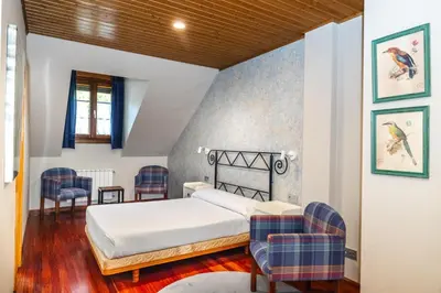 a bedroom with a bed and some chairs at Hotel Casa Miño in Pola de Somiedo