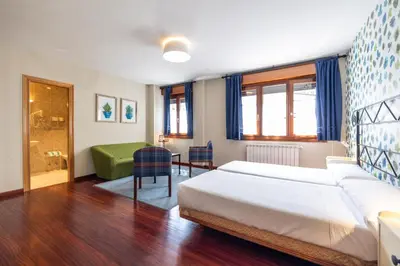 a bedroom with a bed and a table with chairs at Hotel Casa Miño in Pola de Somiedo