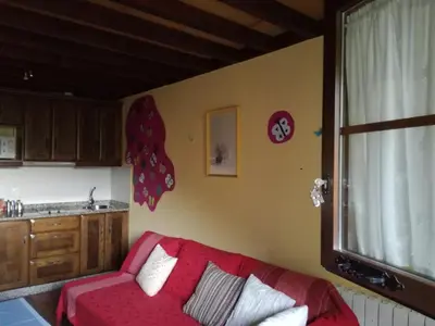 a living room with a red couch in a kitchen at Luna de Vilar in Vilarpescozo