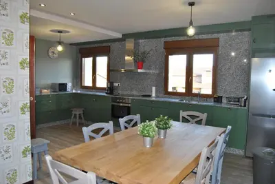 a kitchen with a wooden table and a kitchen with green cabinets at Casa Loisiana in O Pino