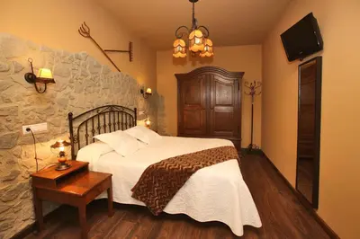 a bedroom with a bed and a stone wall at Apartamentos lagunas in Castropol