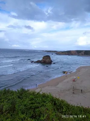 a beach with a group of people standing on the beach at Apartamentos lagunas in Castropol