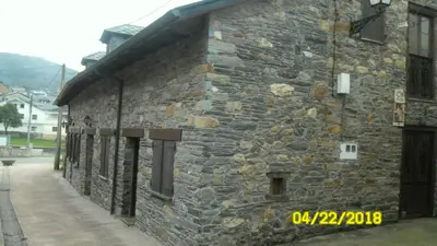 a stone building on a street with a sidewalk at Casa los Ancares in Vega de Espinareda