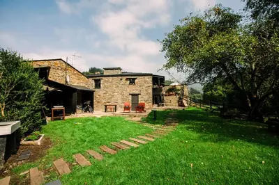 an exterior view of a stone house with a yard at Casa Calma Rural in Taramundi