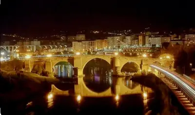 a bridge over a river with a city at night at María Belkis ll in Ourense