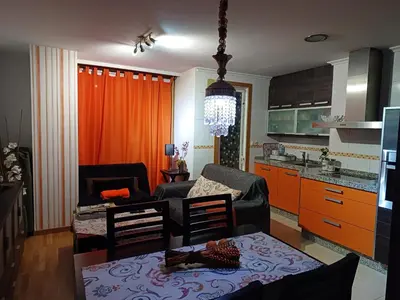 a living room with a table and a kitchen with orange cabinets at María Belkis in Ourense