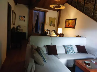a living room with a white couch with pillows at La casita de la señora María in Ponferrada