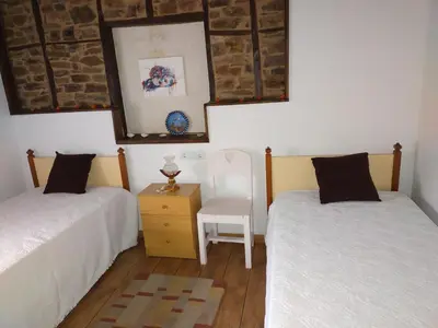 a bedroom with two twin beds and a chair at La casita de la señora María in Ponferrada