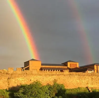 a rainbow in the sky over a building with a wall at La casita de la señora María in Ponferrada