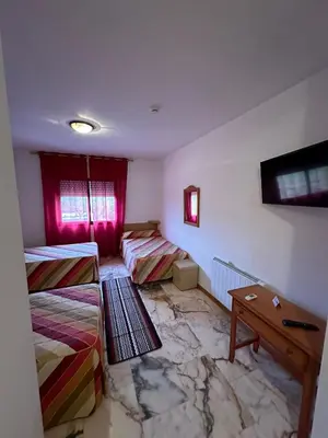 a room with two beds and a table in it at P Residencia PIVIDAL in Picaraña