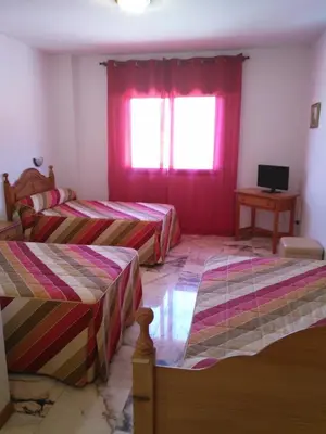 a room with two beds and a window and a desk at P Residencia PIVIDAL in Picaraña