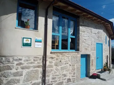 a stone house with blue doors and windows at Casa Antoni@ in Parada del Sil