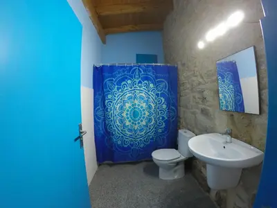 a bathroom with a blue shower curtain and a toilet and sink at Casa Antoni@ in Parada del Sil