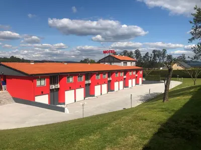a red and white building with a parking lot at Motel Venus Santiago in Luou