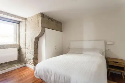 a bedroom with a white bed and a brick wall at Luxury apartment-free parking in Santiago de Compostela