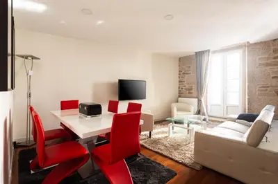 a living room with a white table and red chairs at Luxury apartment-free parking in Santiago de Compostela