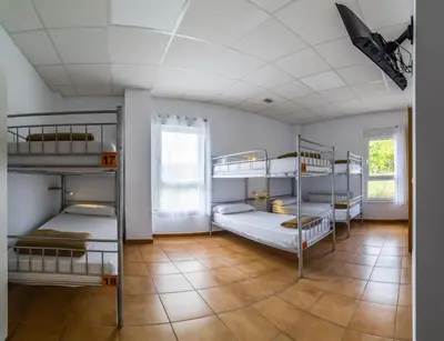 a room with four bunk beds and a tile floor at Albergue Espiritu Xacobeo in O Pedrouzo